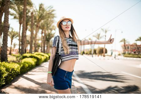 Travel Woman Hitchhiking. Beautiful Young Female Hitchhiker By The Road During Vacation Trip