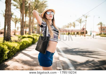 Travel Woman Hitchhiking. Beautiful Young Female Hitchhiker By The Road During Vacation Trip
