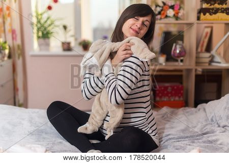 Pregnant woman dreaming and holding baby's clothes.