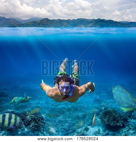 Underwater shoot of a young man snorkeling in a tropical sea on vacation. Design template