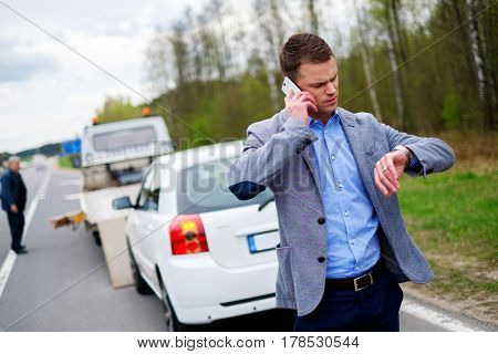 Man calling while tow truck picking up his broken car