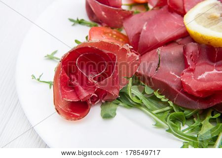 dish of bresaola and aragula and lemon