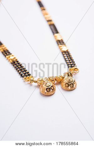 close-up photo of a Mangalsutra or necklace to worn by a married hindu women, with huldi kumkum and mogra flowers or Jasminum sambac garland over white background