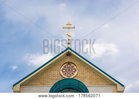 Golden Russian orthodox cross at the orthodox church roof top against blue sky