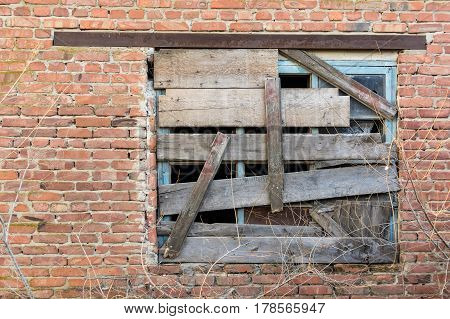 Obsolete demolished boaded up window on red brick wall