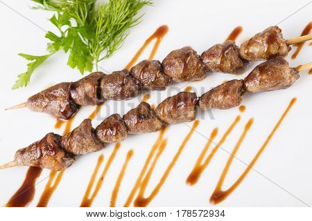 Grilled chiken hearts with sauce on a white background