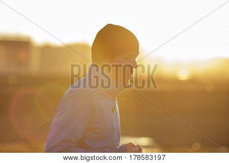 A Young Man  Runs In The Morning At Sunrise. Play Sports And Lead An Active Lifestyle. Low Contrast
