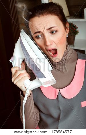 Woman touches a face by hot steaming iron sole