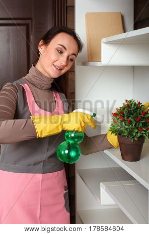 Woman in uniform water the flowers with spray
