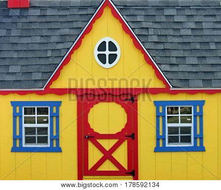 Colorful Yellow Wooden Playhouse with Red and Blue Trim