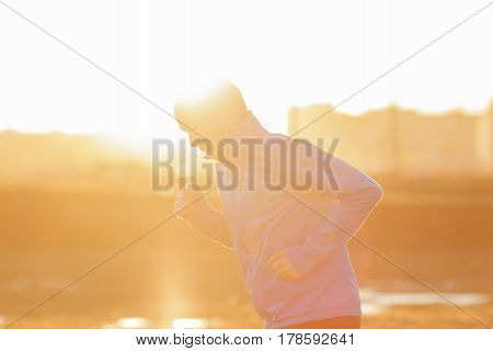 A Young Man  Runs In The Morning At Sunrise. Play Sports And Lead An Active Lifestyle. Low Contrast