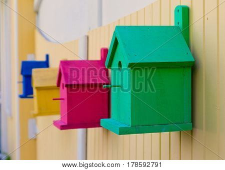 Colorful bird houses on a fence.