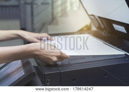 woman hands putting a sheet of paper into a copying device