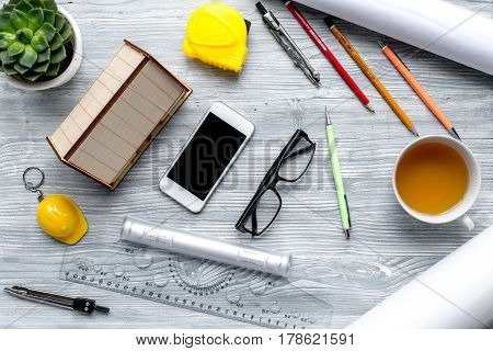 architect working desk with cup of tea, phone and glasses on light wooden background top view