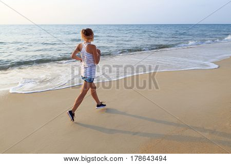 Young woman running during sunrise on a sandy beach