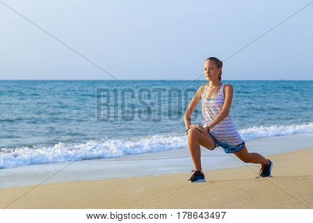 Young girl doing stretching on the beach