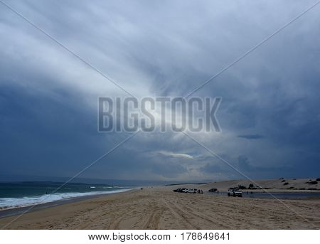 Horizontal landscape of the beach with cars. 4wd cars at Crokers creek (Belmont - Nine Miles - Beach NSW Australia). Redhead Point in the background.