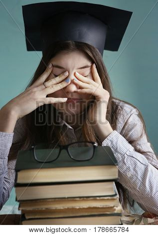 Teenager Student Girl In Graduation Cap With Bood Pile Tired Eyes