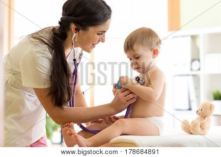 Cute woman pediatrician examining of baby kid with stethoscope