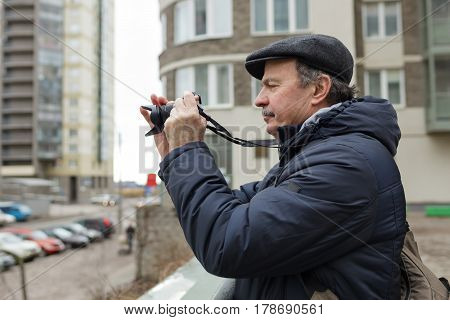 An Elderly Man With A Mirrorless Camera Chooses A Frame On The Street