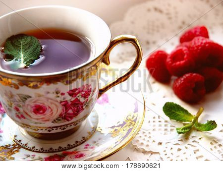 Black tea in a pretty Cup still life tea with raspberries and mint.