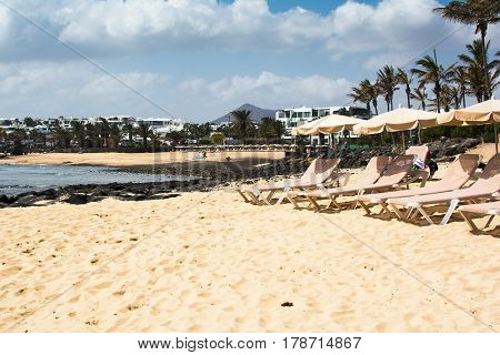 Sun loungers on sand in Playa Las Cucharas beach in Costa Teguise Lanzarote Canary islands selective focus