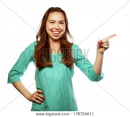 Young smiling woman points a hand with positive facial expressio