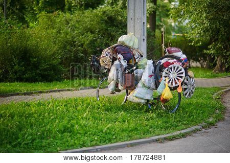 The ragman's bicycle on a green lawn. Lonely standing bike with plenty of old unnecessary things. Contrast with fresh young greens.