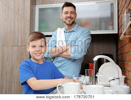 Dad and son doing the washing up in kitchen