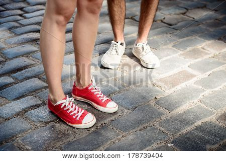 Close up photo of couple's legs in keds standing at street. Copy space.
