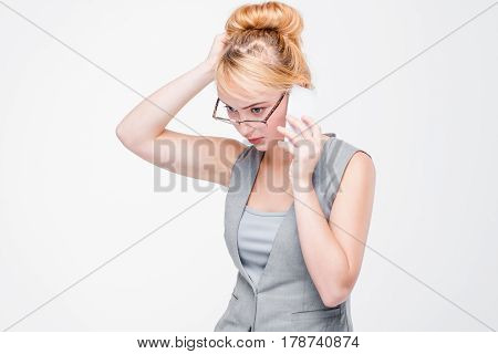 Stressful young woman talking on mobile phone. Anxiety, hard problems, tension situation, difficulties, troubles. Grey background with copy space.