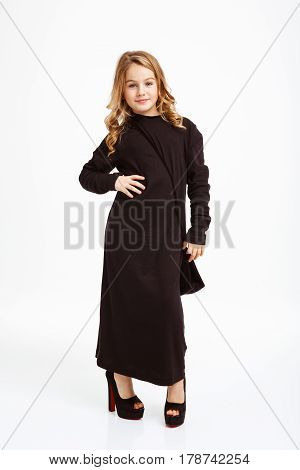 Nice blonde girl in black maxi dress posing with hand on hips, looking straight.