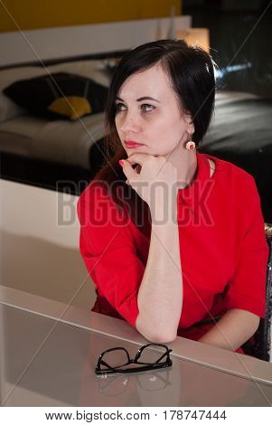 Beautiful Girl Sitting At A Table In A Red Dress,