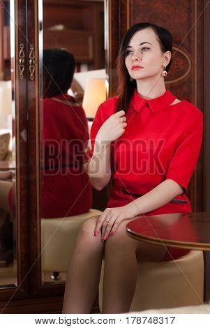 Beautiful Girl Sitting At A Table In A Red Dress,