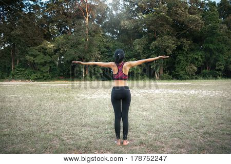 Healthy woman doing Yoga meditation on green lawn in plublic park Singapore.
