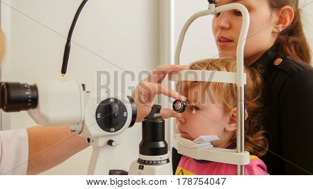 Child's ophthalmology - doctor optometrist checks eyesight for patient - little girl, telephoto