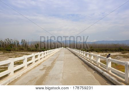 a white stone bridge over the river sutlej in the countryside of the punjab north india under a blue cloudy sky