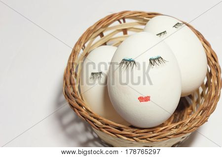 Concept Easter three eggs with eyes and lips in a wicker basket one in the foreground