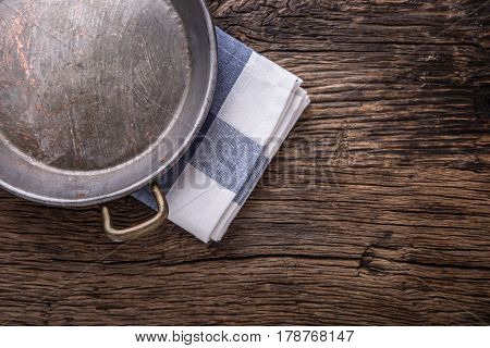 Top view of checkered tablecloth or napkin on empty wooden table.Metal old retro empty pan on oak kitchen table. Top view.