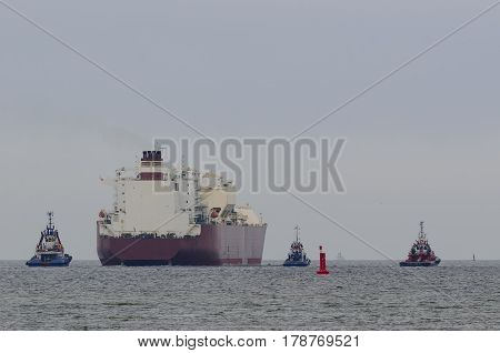 TANKER AND TUGS - Tugboats assists on a big ship sailing on a cruise