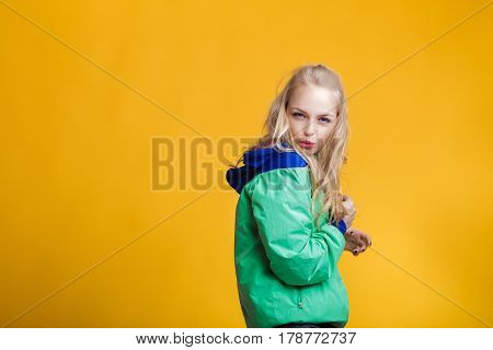 portrait of glamorous beautiful blond woman in sunglasses and blue green jacket on yellow background. hipster summer.