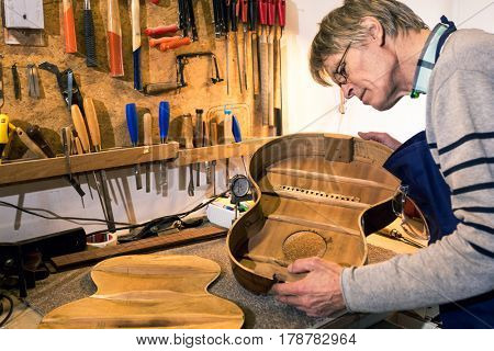 Luthier looking inside the body of an halfway built acoustic guitar