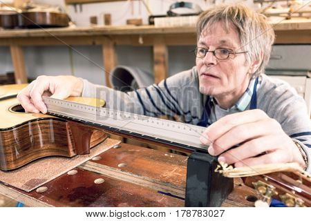 Man presicely measuring the distances between frets on the neck of a guitar
