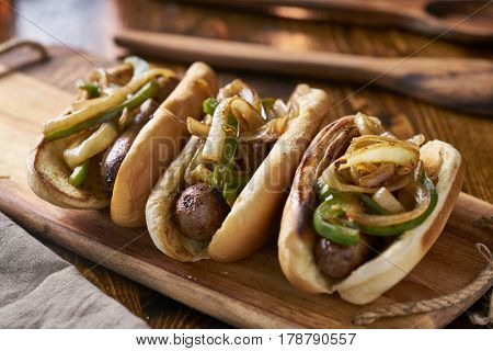 three bratwurst sausages with grilled onions and bell peppers