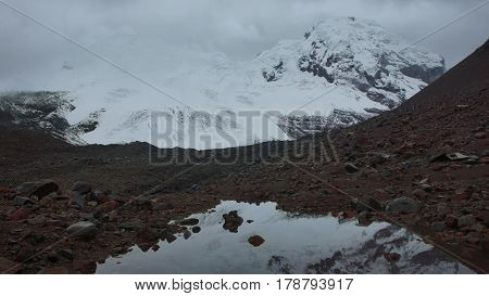 View of the Antisana volcano, reflected in a lagoon on a cloudy day in the Antisana Ecological Reserve - Ecuador