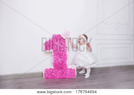 A little girl is standing on her birthday near the number one