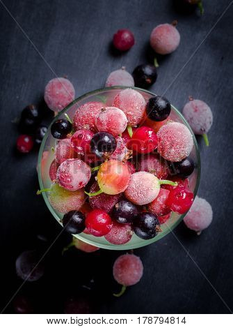 Frozen And Fresh Berries In A Glass Pial On A Black Background.