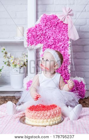 Little girl eating cake in white dress