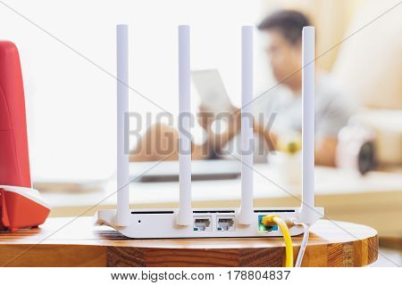closeup of a wireless router and a man using Tablet on living room at home ofiice