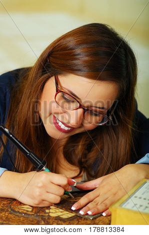 Beautiful young woman wood burning with pyrography pen